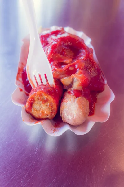 Fourchette blanche en plastique tenant une saucisse blanche recouverte de ketchup — Photo