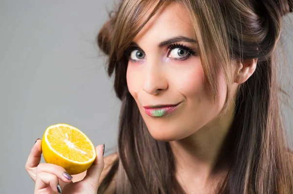 Morena headshot com olhar místico escuro e batom verde segurando um fundo laranja, cinza — Fotografia de Stock