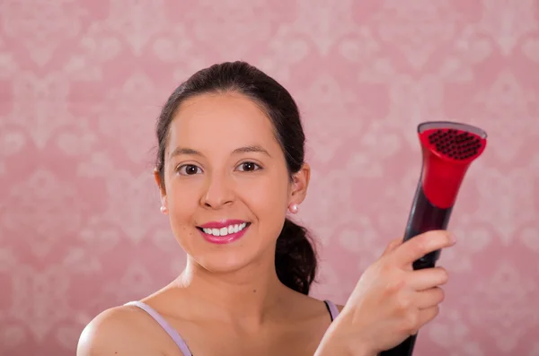 Mujer morena sosteniendo la boquilla de plástico de la máquina de limpieza de vapor, sonriendo a la cámara, fondo rosa — Foto de Stock