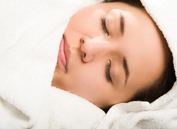 Primer plano de la cabeza joven mujer acostada cómodamente, los ojos cerrados con la cabeza cubierta de toallas blancas — Foto de Stock