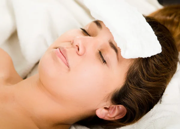 Closeup headshot young woman lying down with eyes closed, white towel pad resting on forehead — Stock Photo, Image