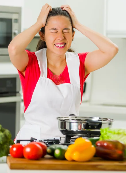 Junge Köchin mit frustrierten Haaren, entmutigtem Gesichtsausdruck, Tisch mit Wasserkocher und Gemüse — Stockfoto