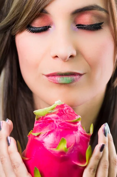 Headshot brunette, dark mystique look and green lipstick, holding up pink pitaya fruit with both hands facing camera — Stock Photo, Image