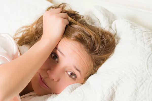 Mujer morena joven disparo en la cabeza en la cama tumbado cabeza descansando sobre la almohada, expresión facial enferma frustrada — Foto de Stock