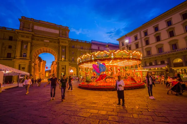 FLORENCE, ITALY - JUNE 12, 2015: Carousel at night iluminated in the middle of the square in Florence. Different forms waitting for childrens, people walking around — Stock Photo, Image