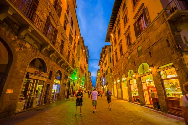 FLORENCIA, ITALIA - 12 DE JUNIO DE 2015: Turistas no identificados caminando por Florencia por la noche, las tiendas están abiertas con un cielo azul — Foto de Stock