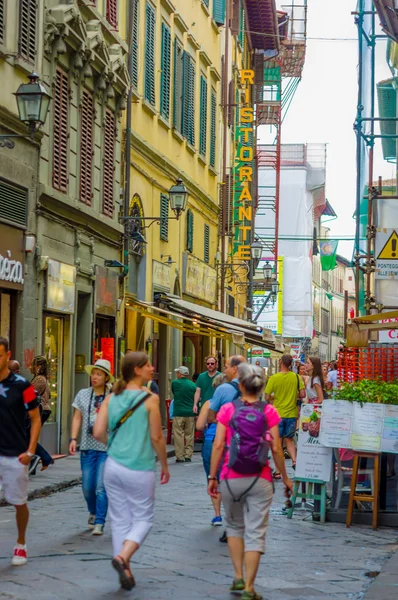 FLORENCIA, ITALIA - 12 DE JUNIO DE 2015: Turistas y personas cruzando una calle comercial, un montón de tiendas a los lados. Una nueva contrucción a la derecha . — Foto de Stock