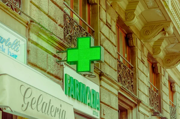 FLORENCE, ITALY - JUNE 12, 2015: Green cross, farmacia sign of medical store. Store sign in historic building, letters on green — Stock Photo, Image