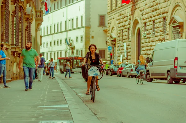 FLORENÇA, ITÁLIA - JUNHO 12, 2015: Mulher livrando-se de uma bicicleta agradável com um saco de compras, caminhantes ao lado e um ônibus que viaja — Fotografia de Stock