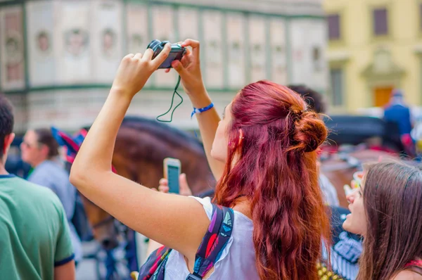 FLORENCIA, ITALIA - 12 DE JUNIO DE 2015: Chica no identificada con el pelo rojo tomando fotografías con una cámara negra en Florencia, vista trasera — Foto de Stock