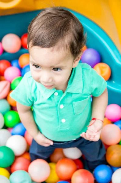 Toddler chłopiec w turkus t-shirt grając z kolorowych kulek plastikowych strzał z kąta — Zdjęcie stockowe