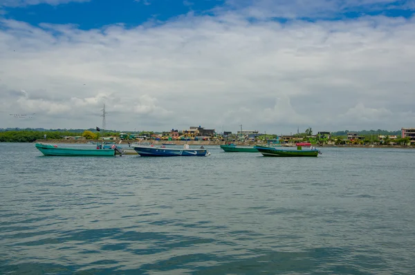 Муйсна, Эквадор - 16 марта 2016 года: традиционные рыбацкие лодки, связанные друг с другом на море, в городе на заднем плане и красивое голубое небо — стоковое фото