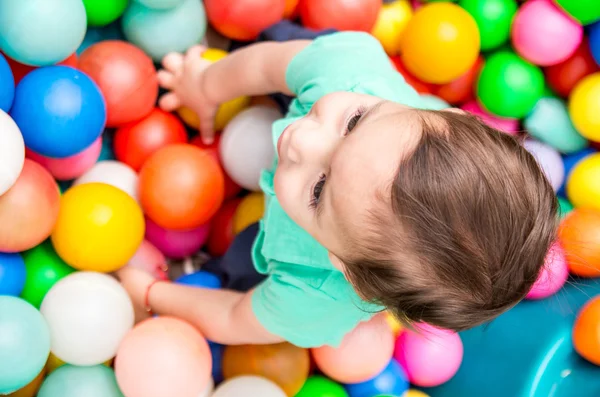 Toddler chłopiec w turkus t-shirt grając z kolorowych kulek plastikowych strzał z kąta — Zdjęcie stockowe