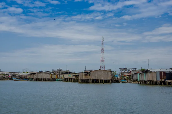 Muisne, Ecuador - 16 de marzo de 2016: Muisne ciudad vista desde el agua, modestas casas de madera sentadas en postes frente al mar Océano Pacífico, edificios de la ciudad de fondo y hermoso cielo azul — Foto de Stock