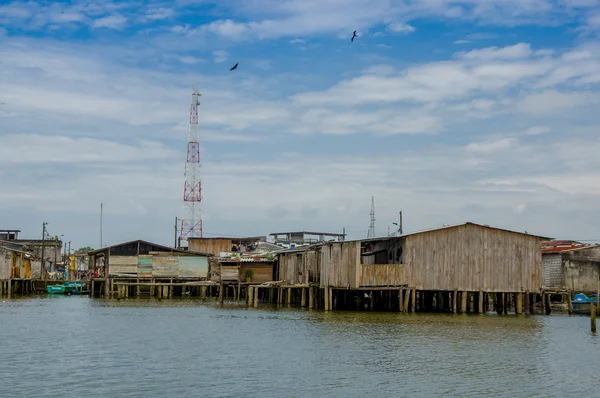 Muisne, Ecuador - 16 de marzo de 2016: Muisne ciudad vista desde el agua, modestas casas de madera sentadas en postes frente al mar Océano Pacífico, edificios de la ciudad de fondo y hermoso cielo azul — Foto de Stock