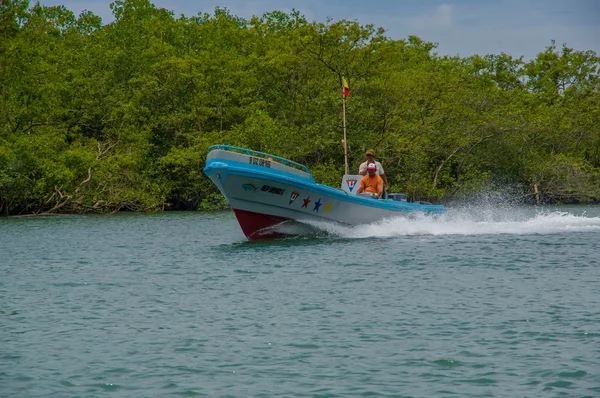 Muisne, Equador - 16 de março de 2016: Dois pescadores locais sentados em seu barco dirigindo ao lado da costa, fundo de vegetação verde — Fotografia de Stock