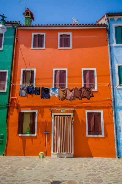 Burano, Olaszország-június 14, 2015: kis ház narancssárga színű, különböző ablakok és nedves ruhák kívül — Stock Fotó