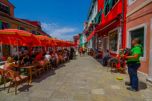 BURANO, ITALIA - 14 DE JUNIO DE 2015: Gente disfrutando afuera, día de verano en Italia, restaurantes con sombrillas afuera — Foto de Stock