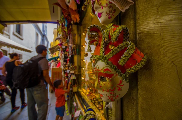 VENICE, ITALY - JUNE 18, 2015: Red and gold beautiful mask in a souvenir shop in Venice, selective focus. Turists looking at the back — Stock Photo, Image