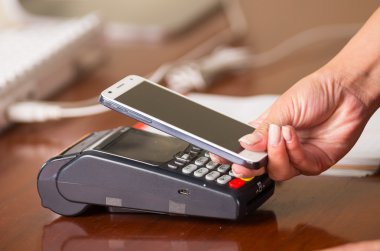 Alışveriş hesapları ödemek için kolay ve hızlı bir şekilde yakınındaki bir kredi kartı makinesi, el holding cep telefonu cep telefonu
