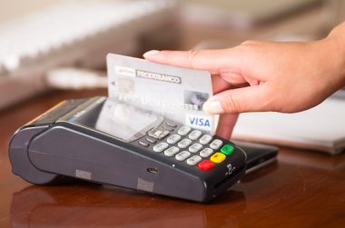 Visa kredi kartı swiping tarafından bir terminal kadın elinde. Ahşap masa ve kağıtları arkasında
