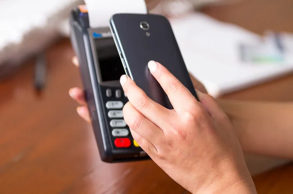 Primer plano de teléfono móvil negro y máquina de tarjeta de crédito, escaneo de código para pagar la factura — Foto de Stock