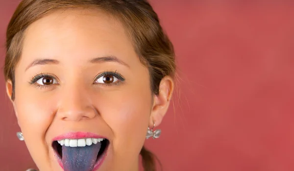 Woman with open mouth spreading tongue colored in blue with pink background — Stock Photo, Image