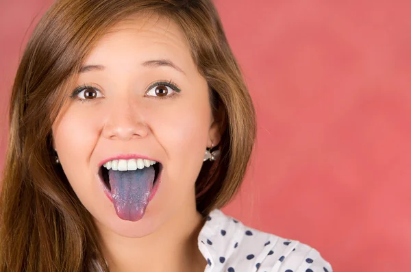 Femme à bouche ouverte écartant la langue colorée en bleu avec fond rose — Photo