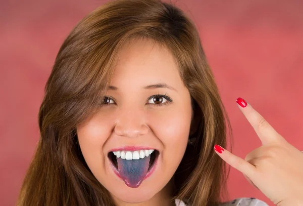 Woman with open mouth spreading tongue colored in blue with pink background with colored nails — Stock Photo, Image