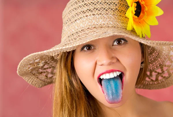 Mooie gebreide muts op beige kleur met een zonnebloem op het meisje met het met blauwe tonge uitsteekt — Stockfoto