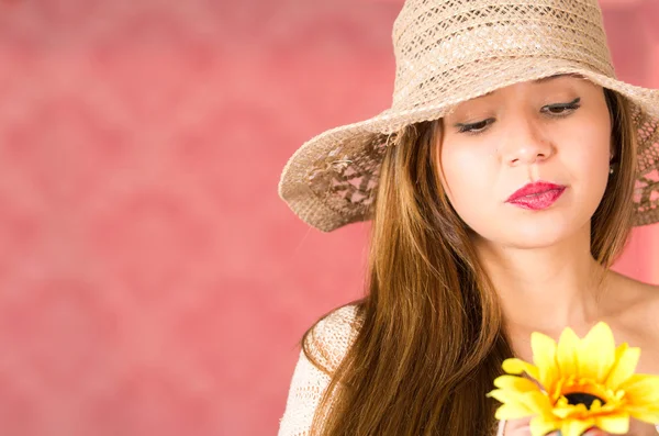 Woman with nice hat looking a sunflower in her hand, pensative and serious mood — Stock Photo, Image