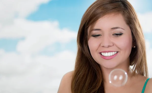 Mulher sorridente olhando bolhas de sabão flutuando no ar, humor concentrado — Fotografia de Stock