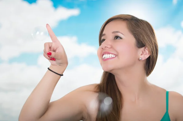 Woman smiling and trying to touch a soap bubbles, happy playing — Stock Photo, Image
