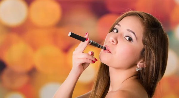 Mujer fumando un cigarrillo electrónico negro, dos dedos sosteniendo con fondo de color — Foto de Stock