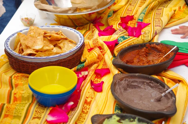 Cuenco de crocantes delicadas tortillas fritas sentadas sobre manteles nativos americanos, junto a diferentes salsas — Foto de Stock