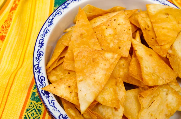 Schüssel mit knusprigen delikaten Tortilla-Chips auf indianischer Tischdecke — Stockfoto