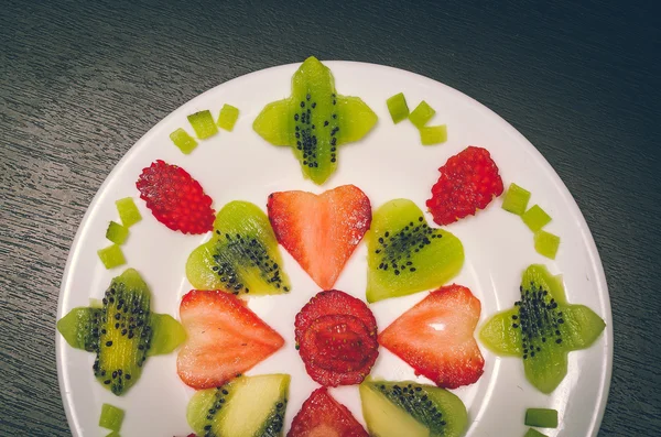 Sliced kiwi and strawberries lying in neatly placed pattern on white plate, as senn from above — Stock Photo, Image
