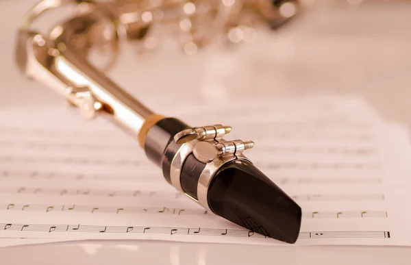 Closeup bocal de saxofone deitado em papel notas musicais — Fotografia de Stock