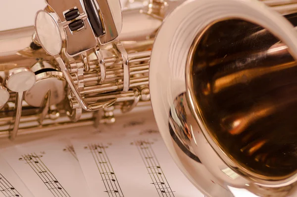 Kısmen closeup görüntülemek parlak saksafon müzik notaları kağıt üzerinde yalan