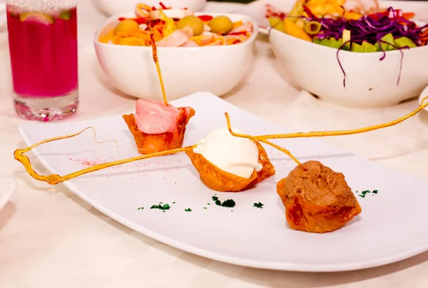 Small crocante dessert cups with cream fillings and caramel strings sitting on white plate, catering concept