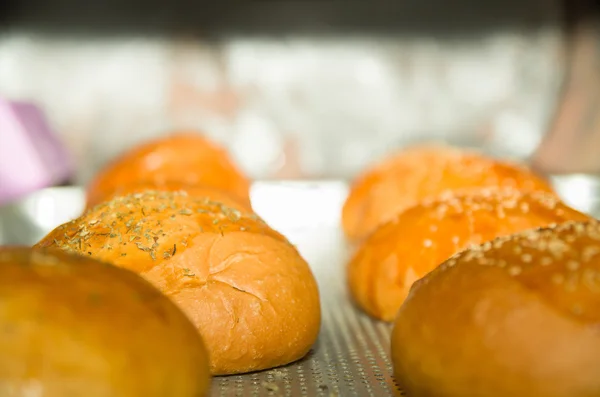 Primo piano focacce di pane appena sfornate con cima di semi di sesamo, seduti su un piano di cottura grigio — Foto Stock