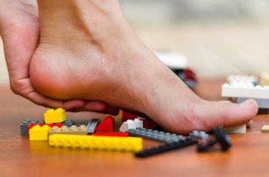 Bir ayak ile bazı legos yerdeki incitir. Çeşitli renkler, kırmızı, beyaz, sarı, gri, siyah