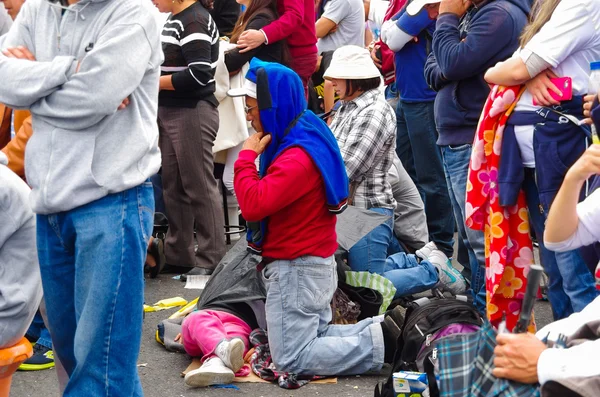 QUITO, ECUADOR - JULY 7, 2015: Orang-orang berlutut di tengah-tengah massa, berdoa. Keluarga di lantai — Stok Foto