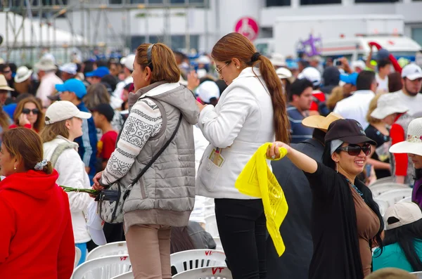 КВИТО, ЕКУАДОР - 7 июля 2015 года: Женщины ждут, чтобы увидеть массовое мероприятие Папы Франциска, одна с мобильным телефоном и другая с желтым флагом — стоковое фото