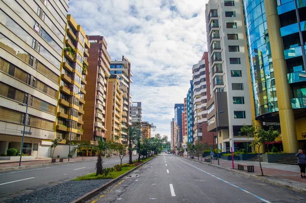 QUITO, ECUADOR - JULHO 7, 2015: avenida importante na cidade, edifícios altos com árvores no meio, dia ensolarado — Fotografia de Stock