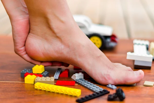 A hand making some massage on a heel of feet after step on colored blocks — Stock Photo, Image