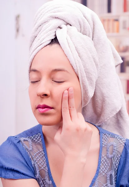 Two fingers covering something in a woman face, towel on her head — Stock Photo, Image