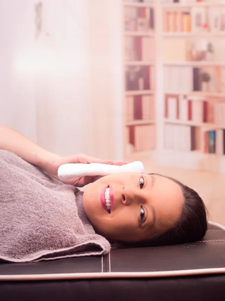 Mujer feliz mintiendo y haciendo algún tratamiento facial, sonriendo y limpiando su cara — Foto de Stock