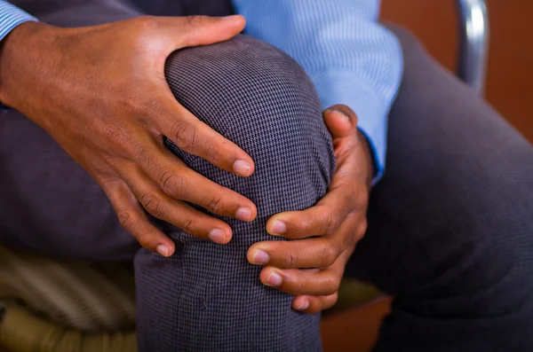 Dolor de rodilla en un hombre, ambas manos sosteniéndolo y haciendo un masaje — Foto de Stock