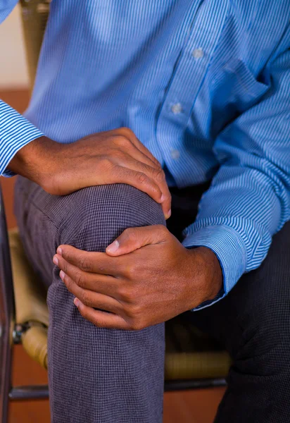 Man handen rond de knie, sterke pijn. Tshirt en broek blauw — Stockfoto